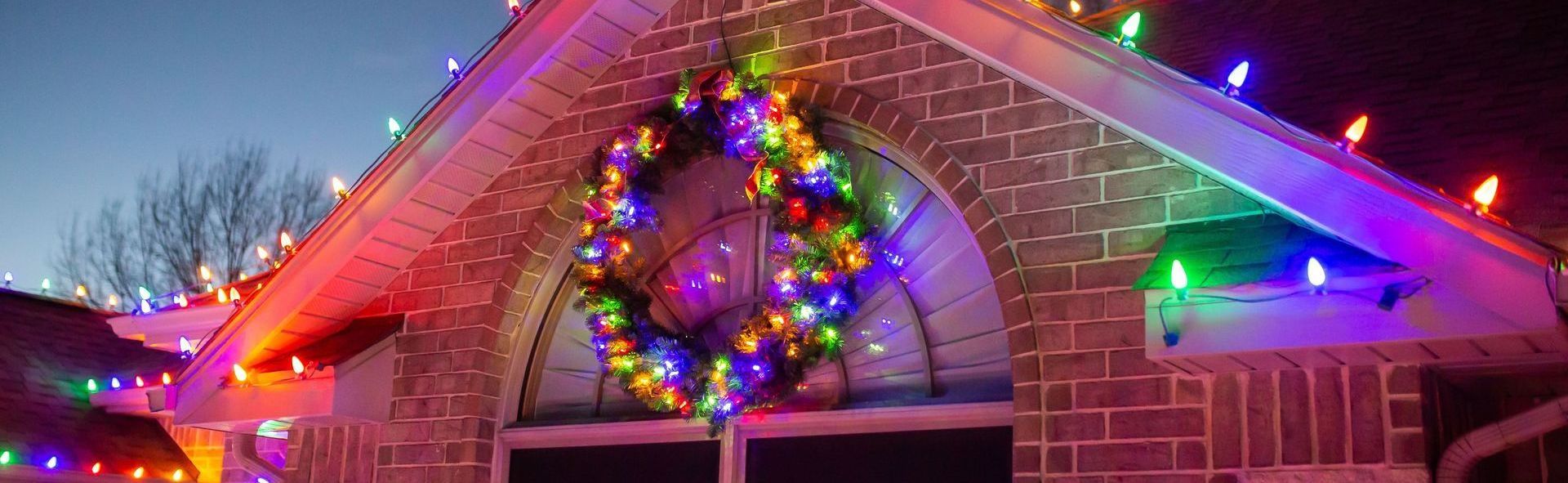A house is decorated with christmas lights and a wreath.