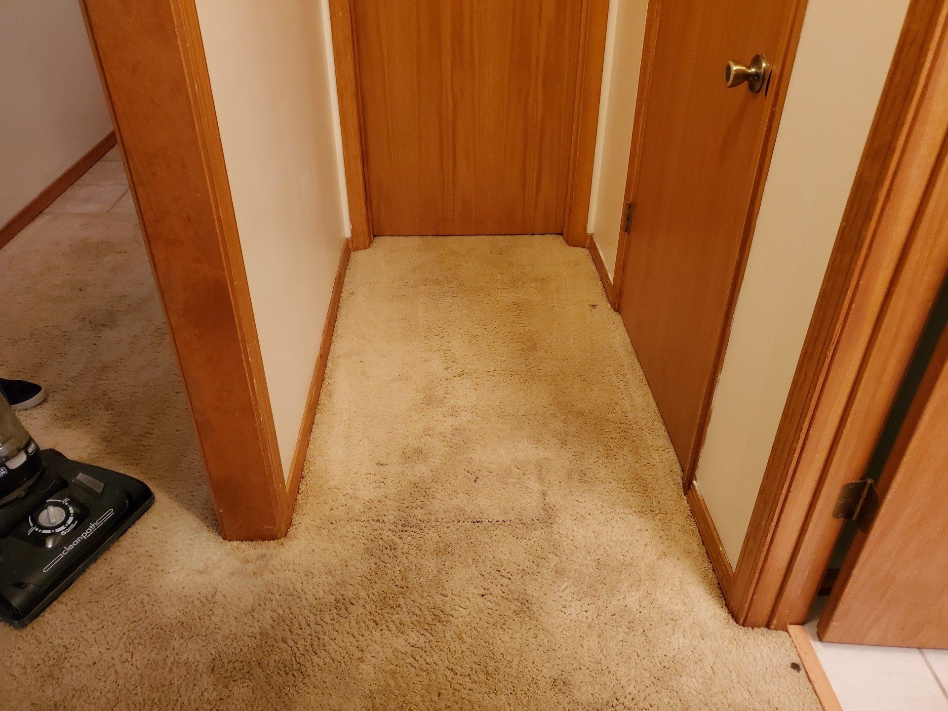 A vacuum cleaner is sitting on the floor in a hallway next to a door.