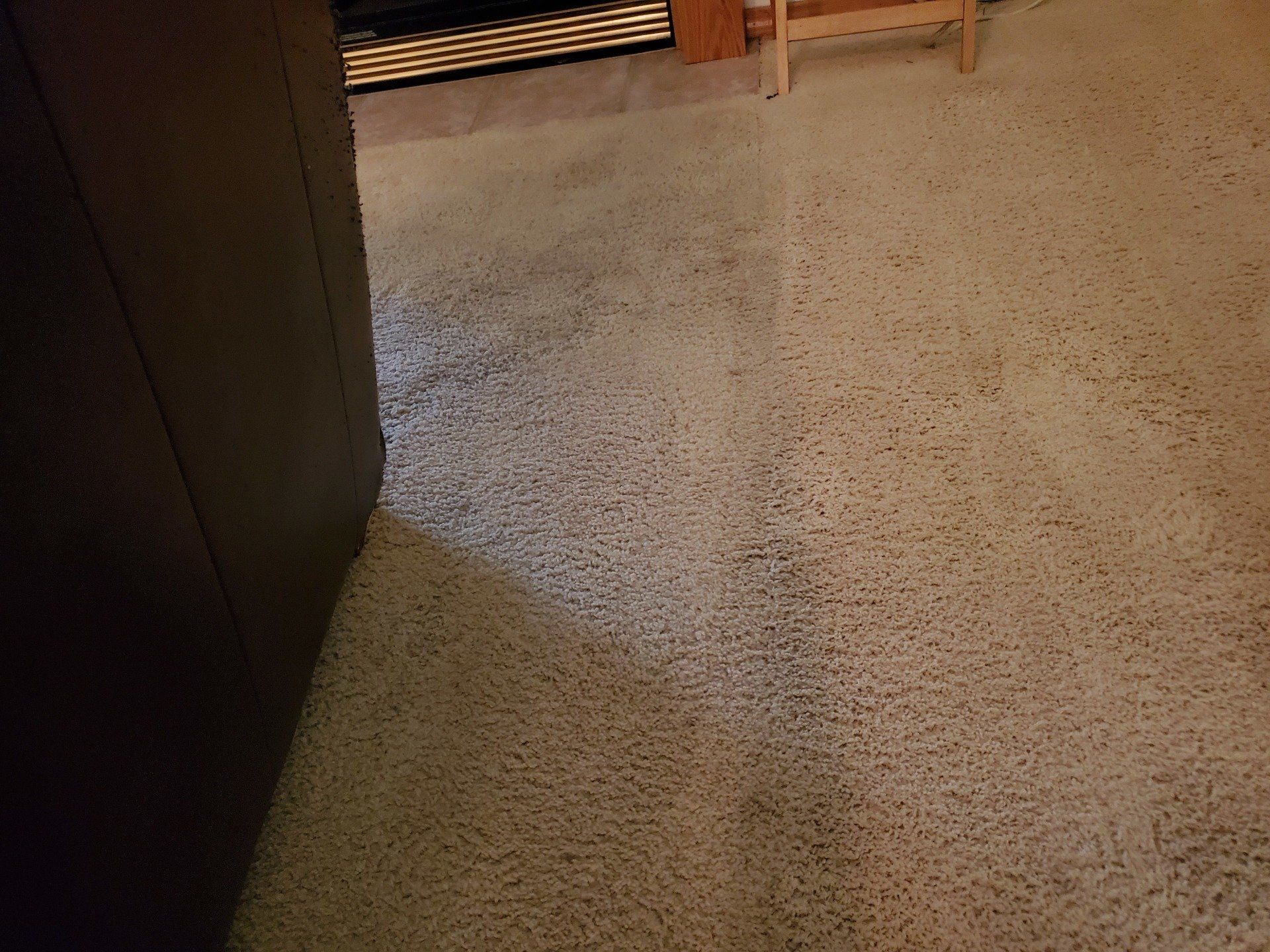 A dirty carpet in a living room next to a fireplace.