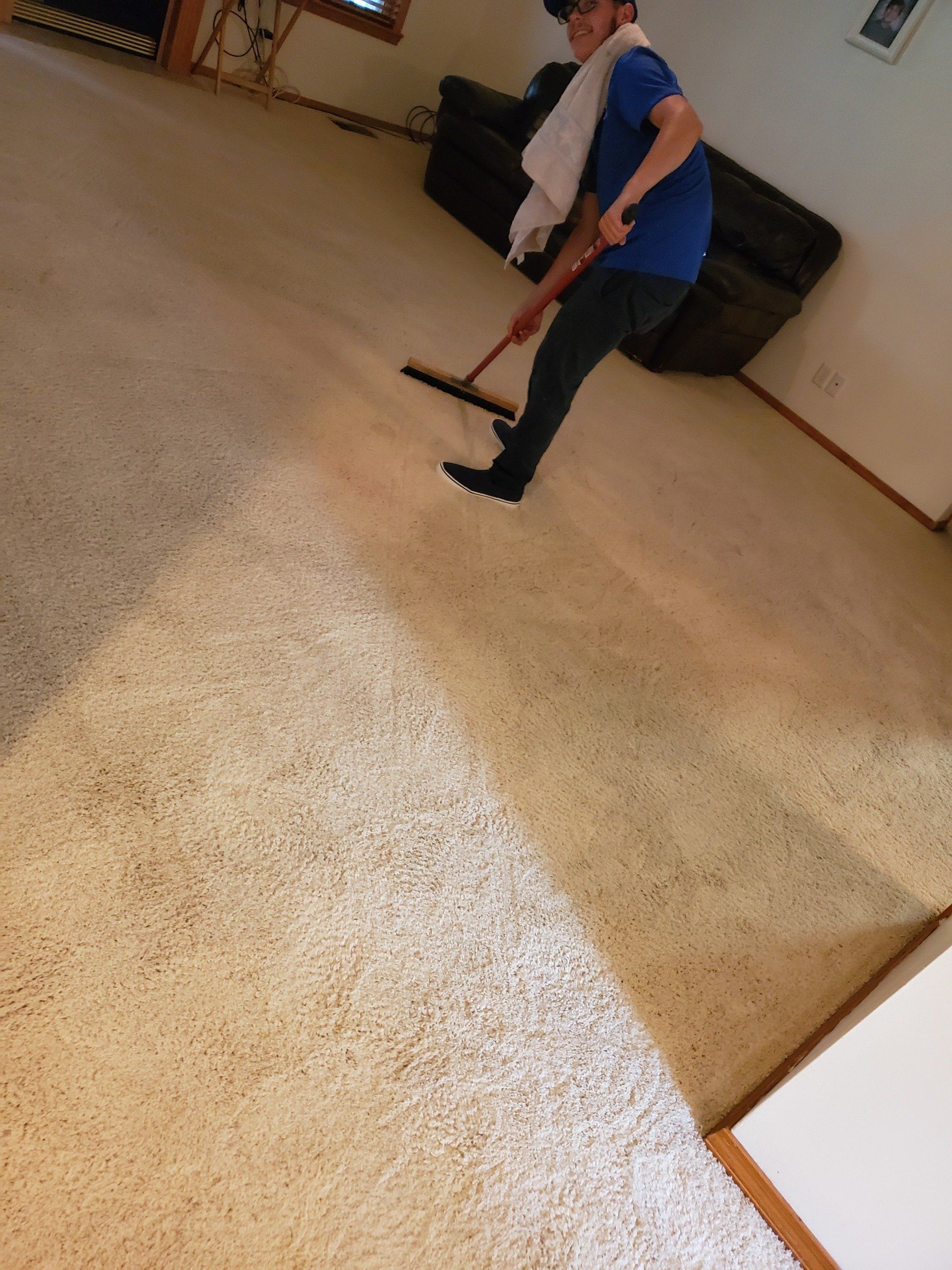 A man is sweeping the floor with a mop in a living room.