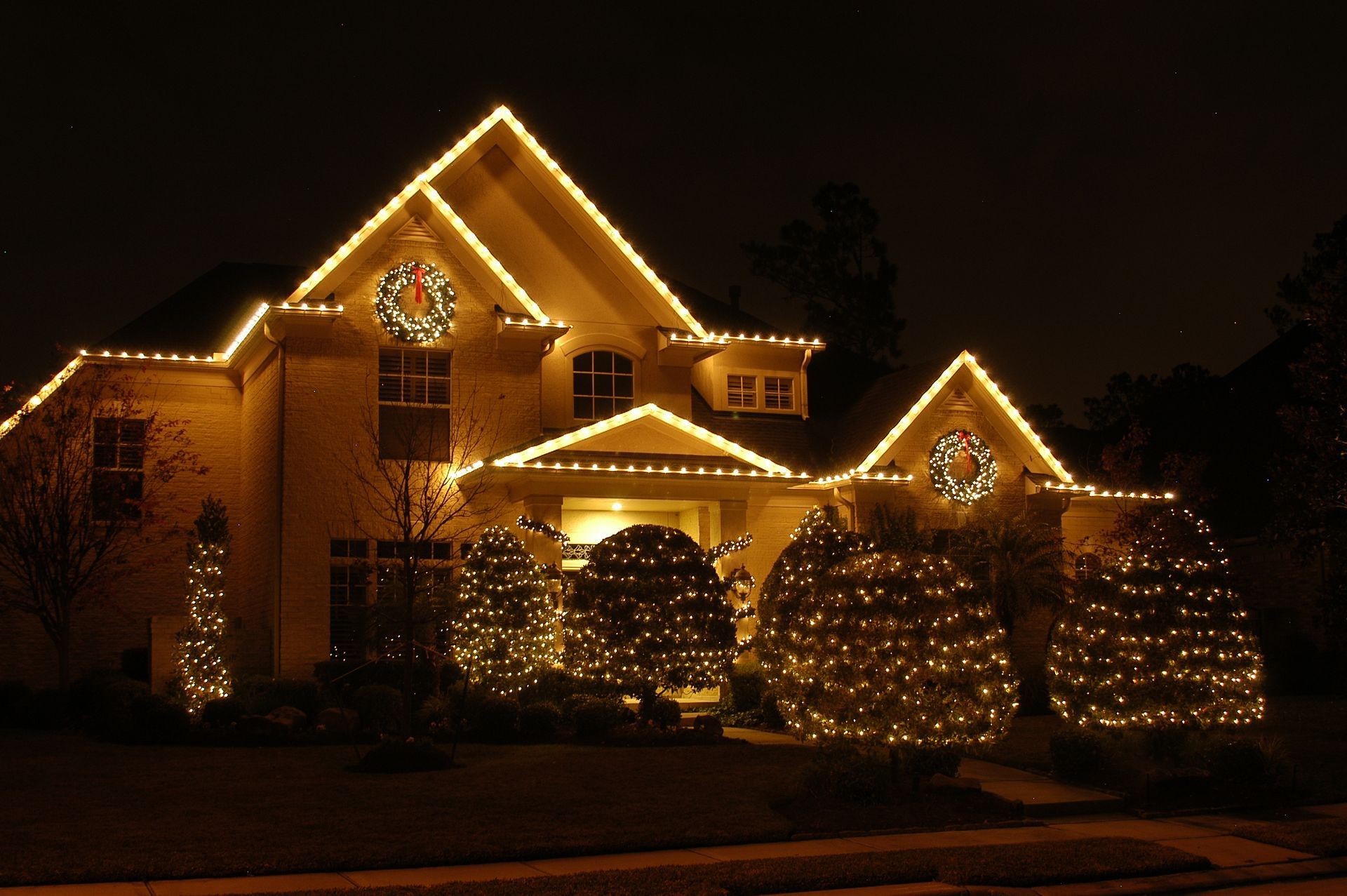 A house decorated with christmas lights and wreaths at night