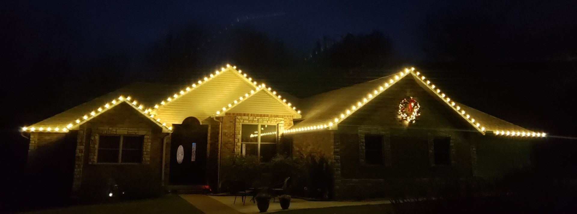 A house with christmas lights on the roof at night.