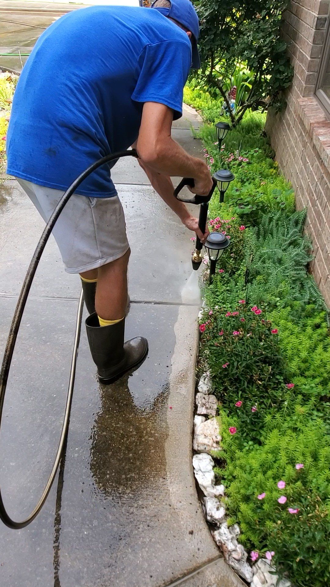 A man is cleaning a sidewalk with a pressure washer.