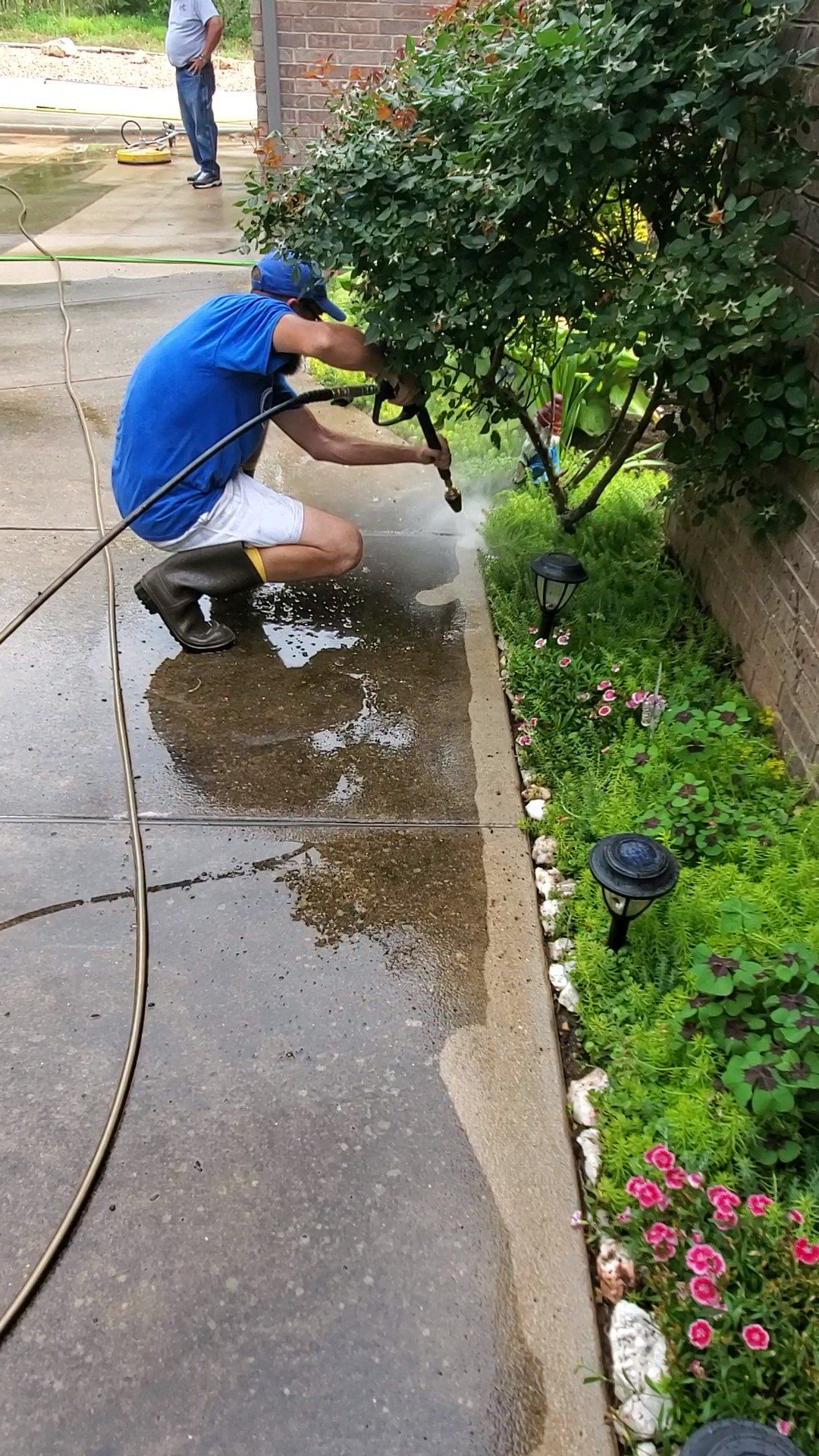 A man is cleaning the sidewalk with a pressure washer.