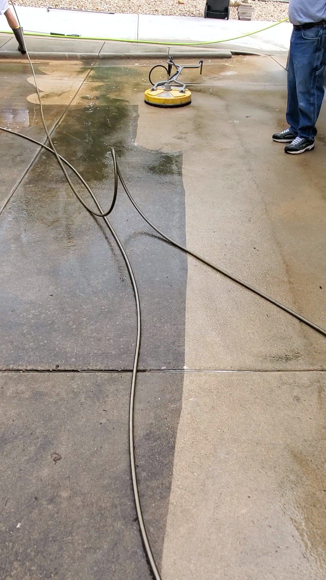 A man is cleaning a concrete driveway with a pressure washer.