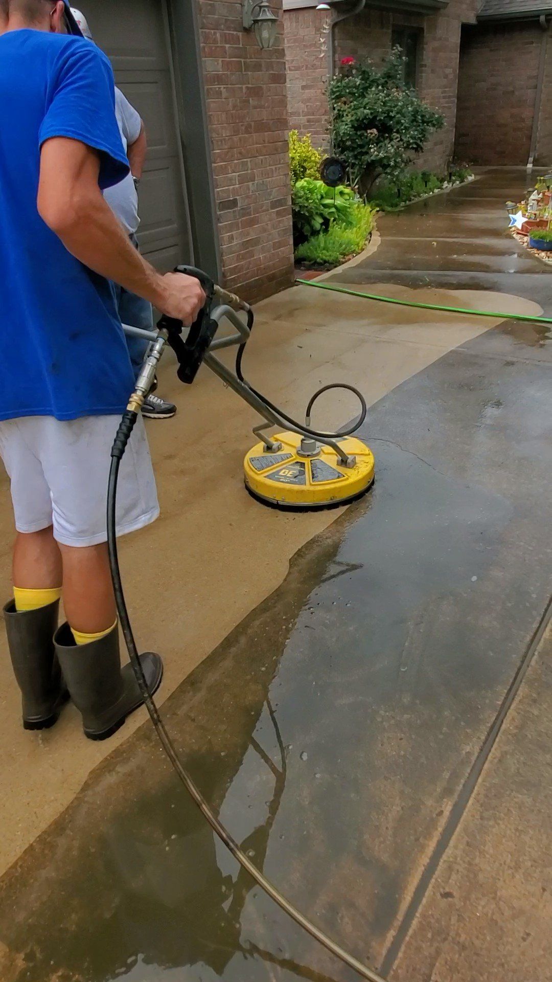 A man is using a pressure washer to clean a driveway.