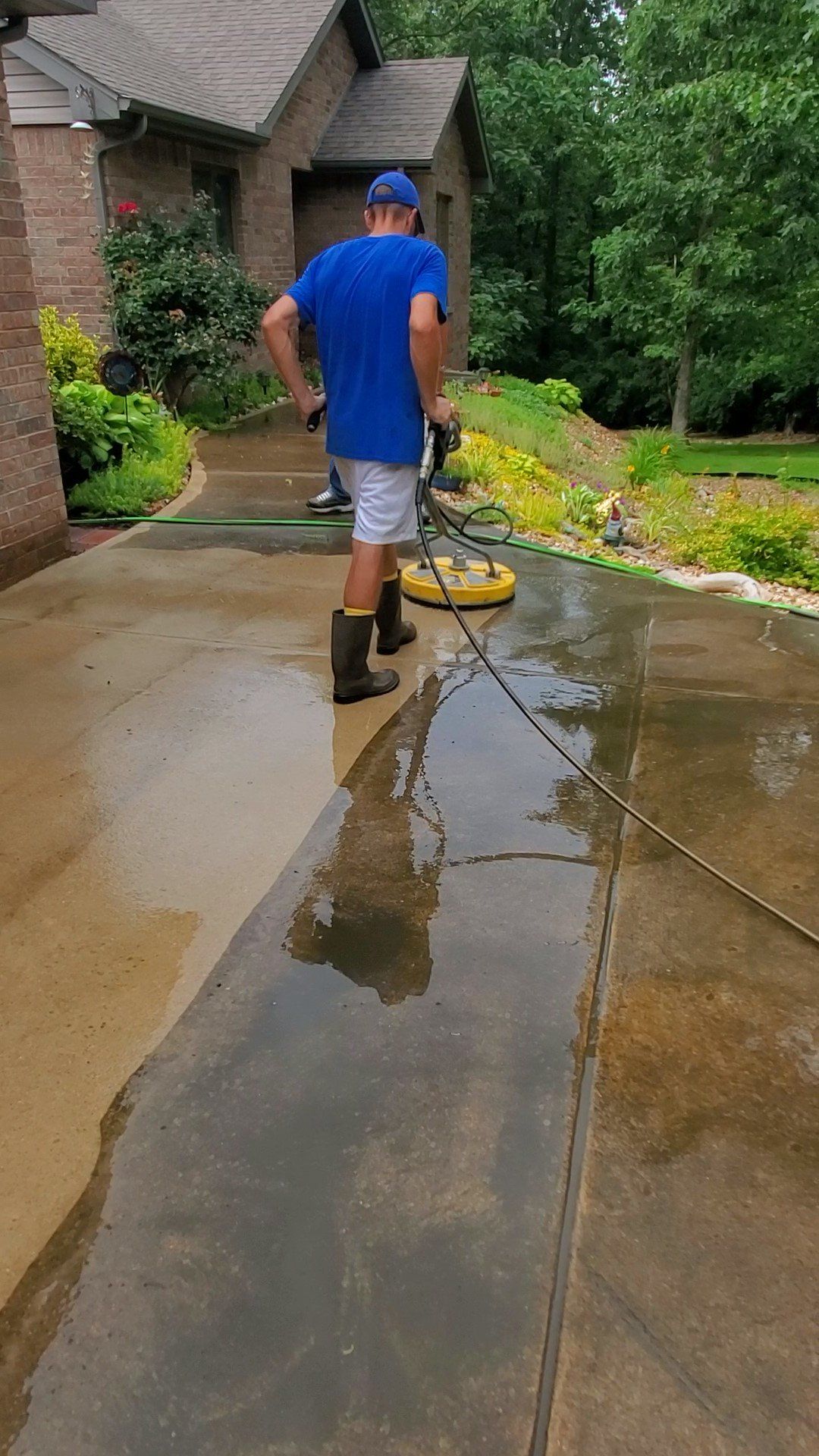 A man is cleaning a driveway with a machine.