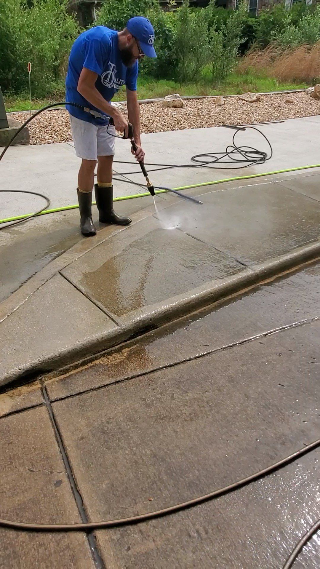 A man is using a high pressure washer to clean a concrete driveway.