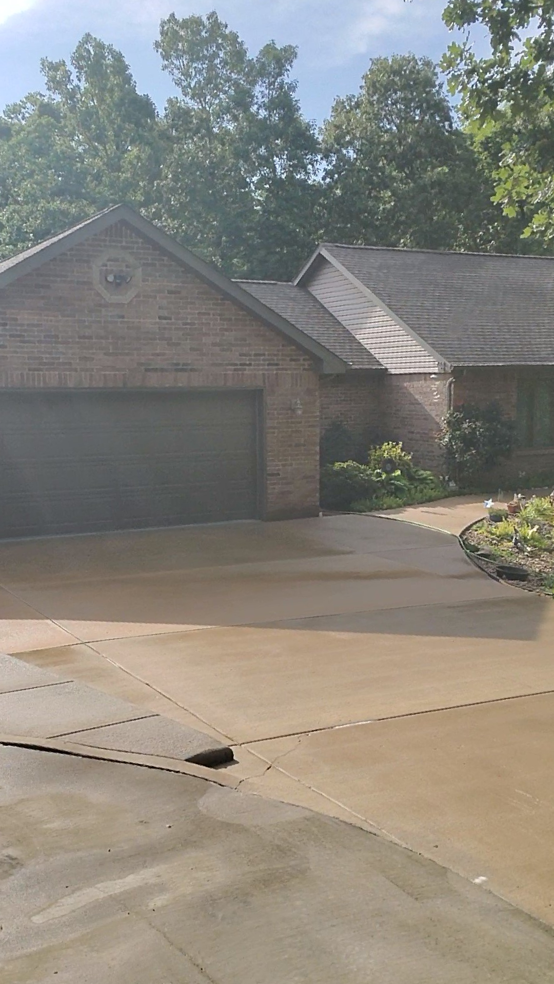 A brick house with two garage doors and a driveway in front of it.