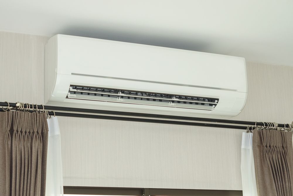 White Wall-mounted Air Conditioner Above Window With Curtains — M.R. Services Air Conditioning Pty Ltd In Taminda, NSW