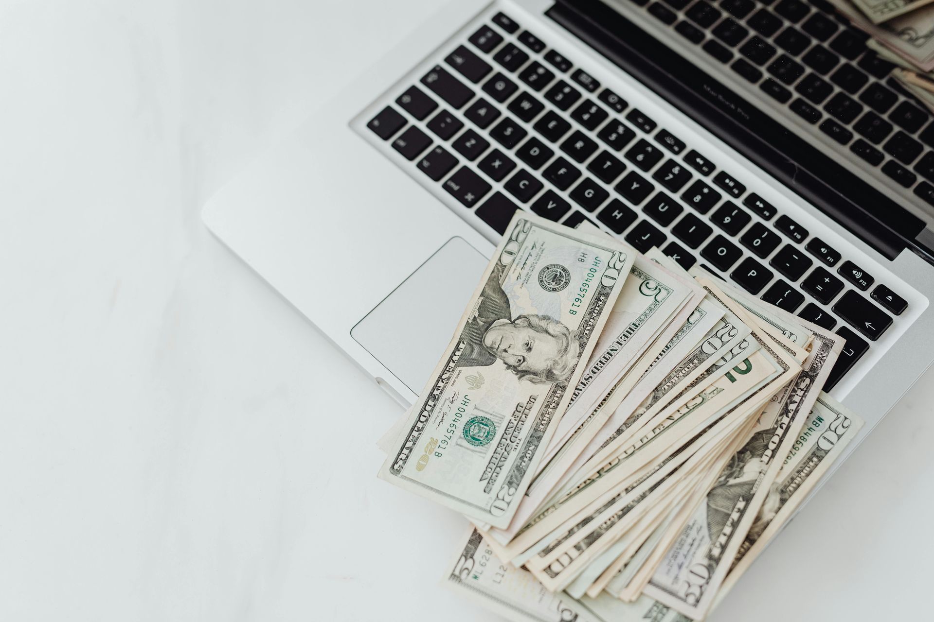 Laptop with cash, white background.