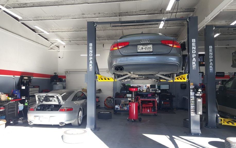 A car is sitting on a lift in a garage.