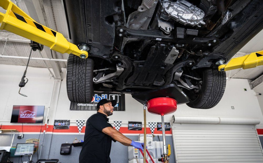 A man is working under a car on a lift in a garage.