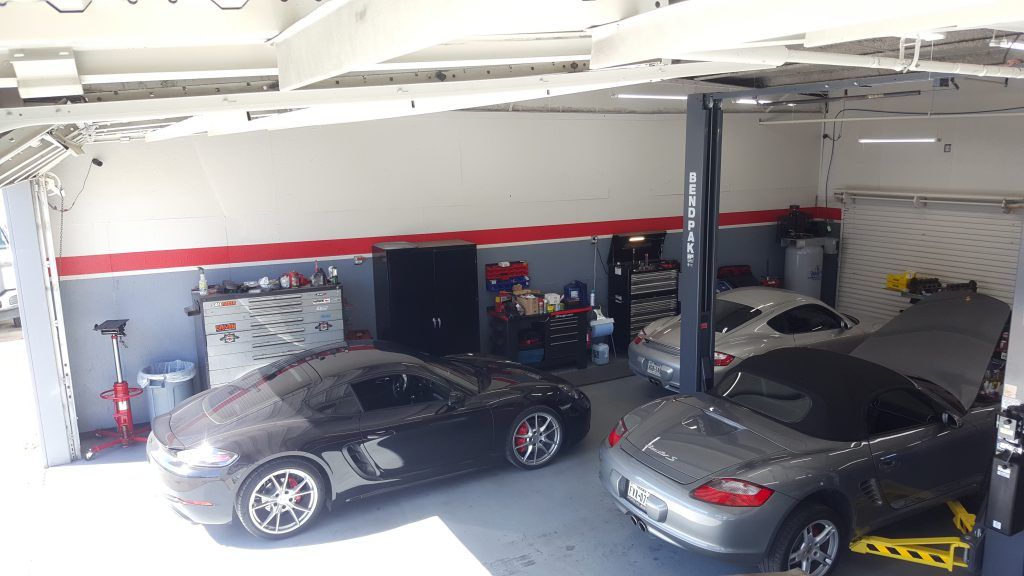 A couple of cars are parked in a garage.