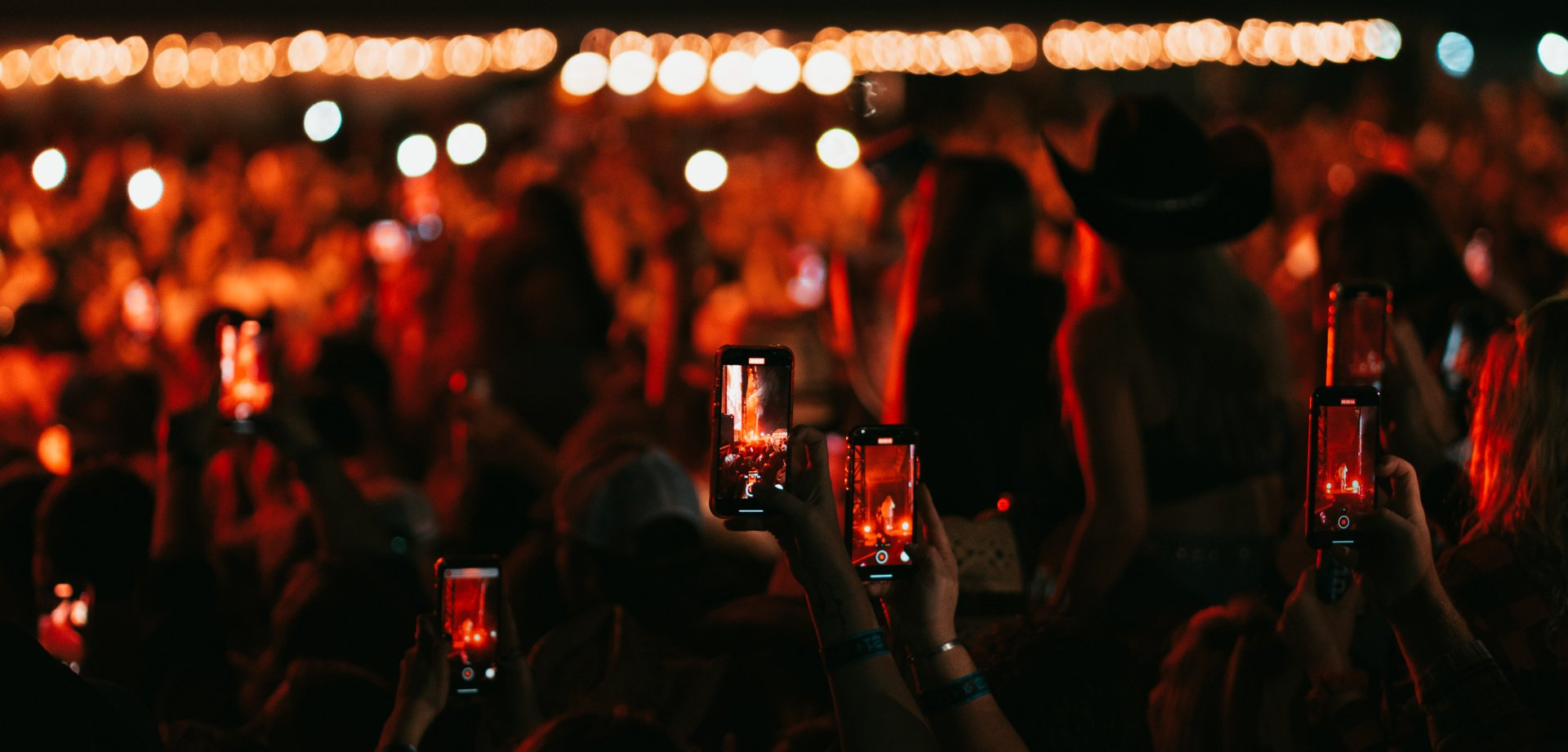 people at live country music concert recording with phones