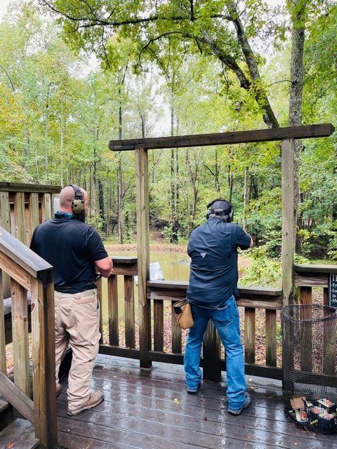 Two men are standing on a deck looking at a pond.