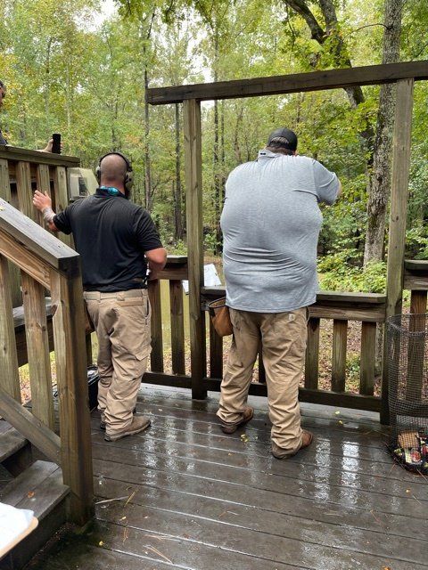 Two men are standing on a deck looking out over a forest.