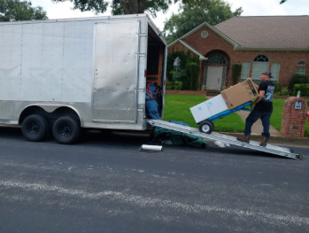 A man pushing a box on a dolly next to a trailer