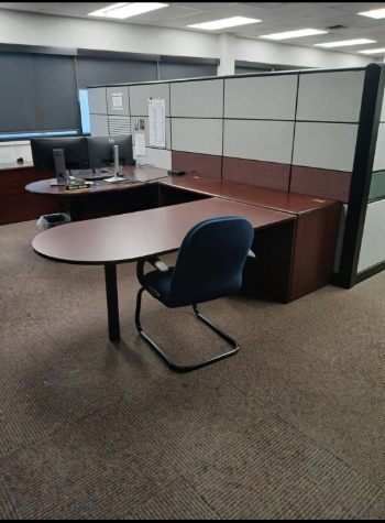 A cubicle with a desk and a chair in it.