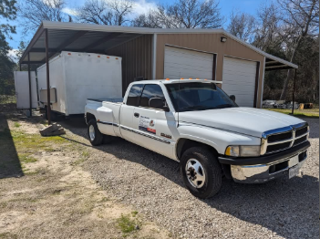 A white truck is parked in front of a garage.