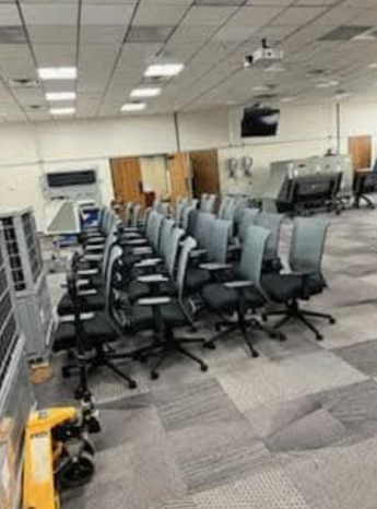 A room filled with rows of chairs and a yellow hand truck.