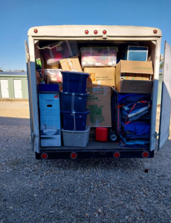 The back of a moving truck filled with boxes and containers.