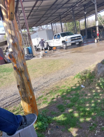 A person is sitting on a bench in front of a truck wash.