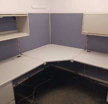 A cubicle with a white desk and purple walls