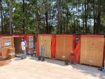 A man is standing in front of a row of wooden boxes.