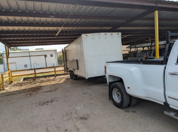 A white truck is pulling a trailer under a covered area