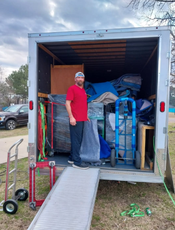 A man is standing in the back of a moving truck.