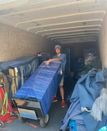 A man is standing in the back of a truck holding a large blue box.