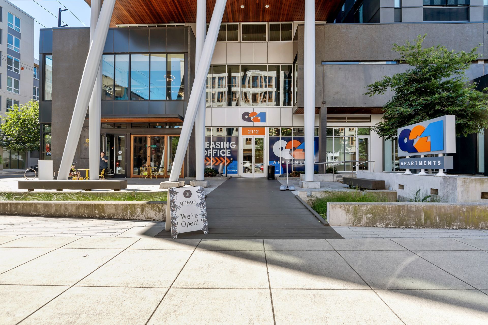 A large building with a clock on the sidewalk in front of it