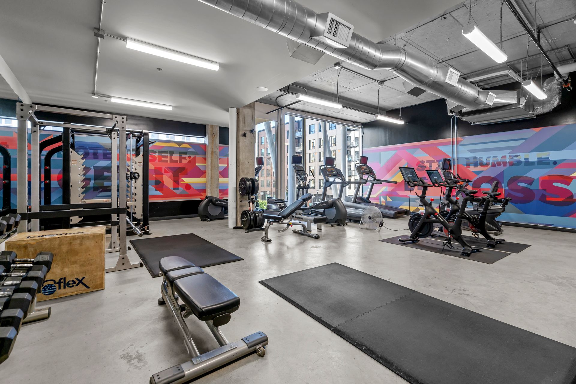 A large gym with a lot of equipment and a mural on the wall.