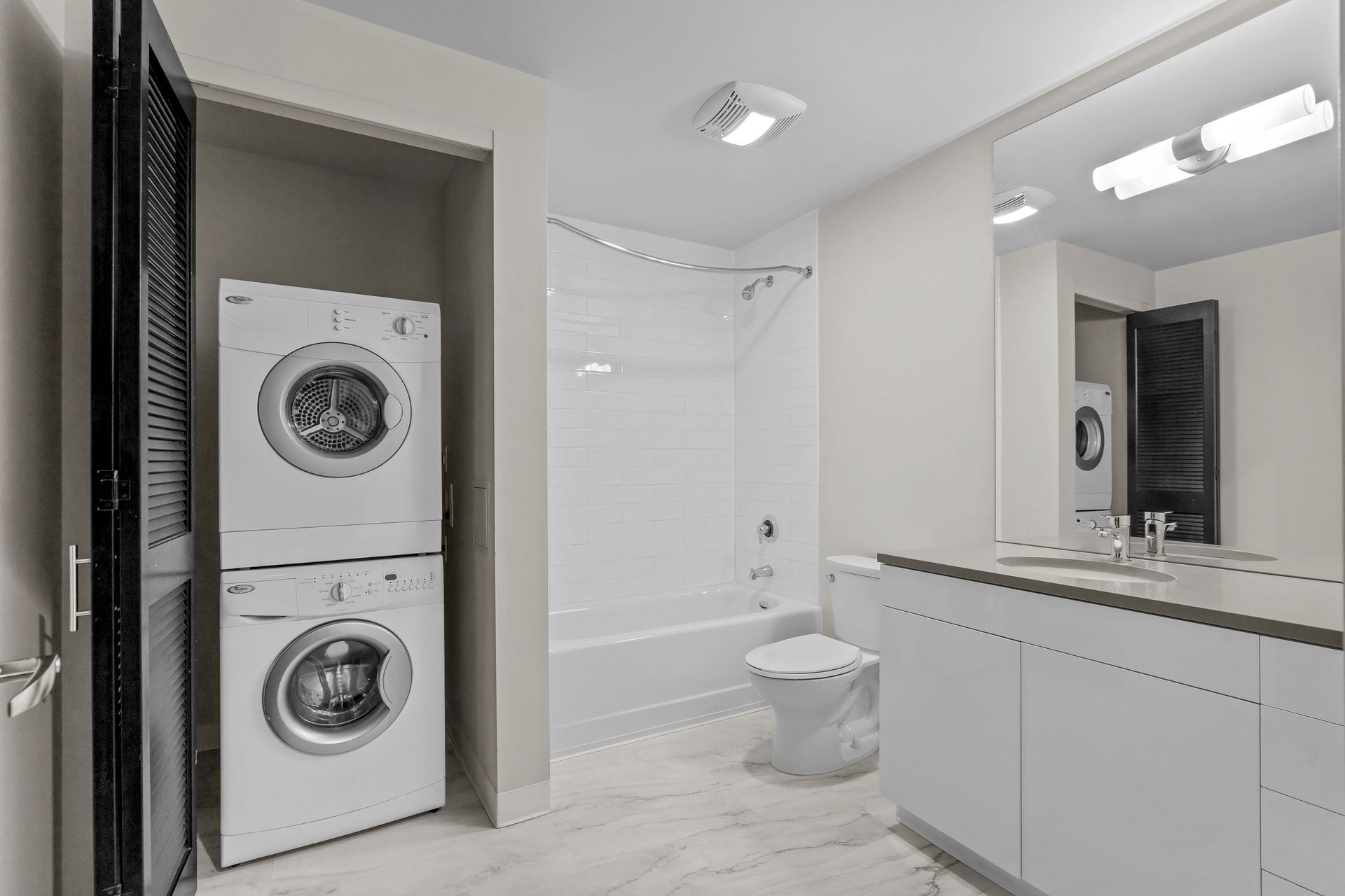 A bathroom with a washer and dryer stacked on top of each other.
