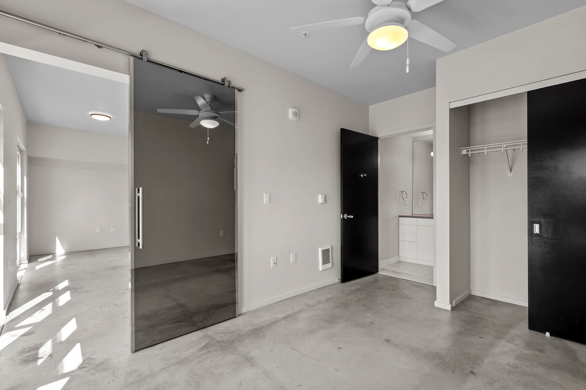 An empty room with a ceiling fan and sliding glass doors.