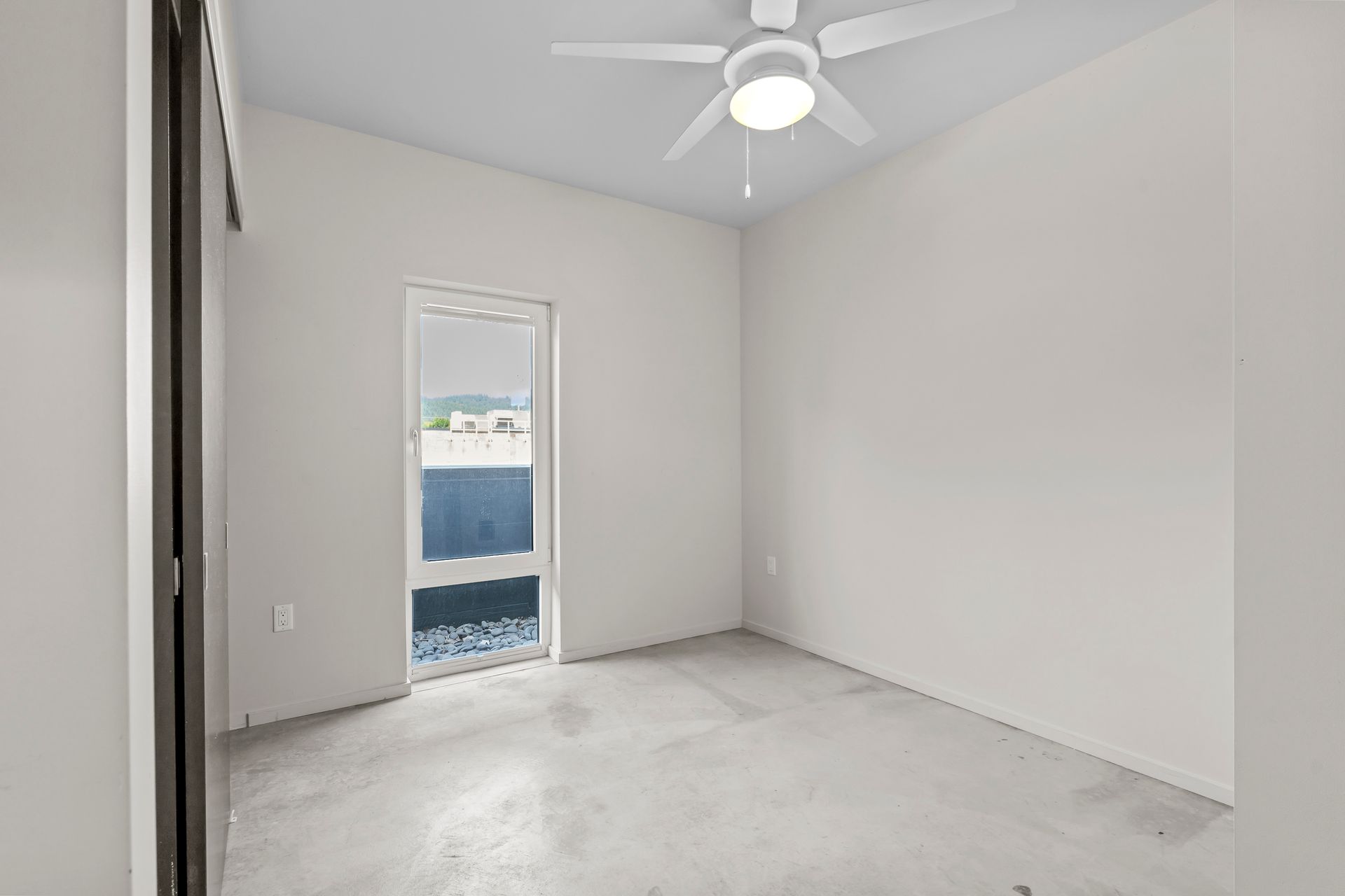 An empty room with a ceiling fan and a door.