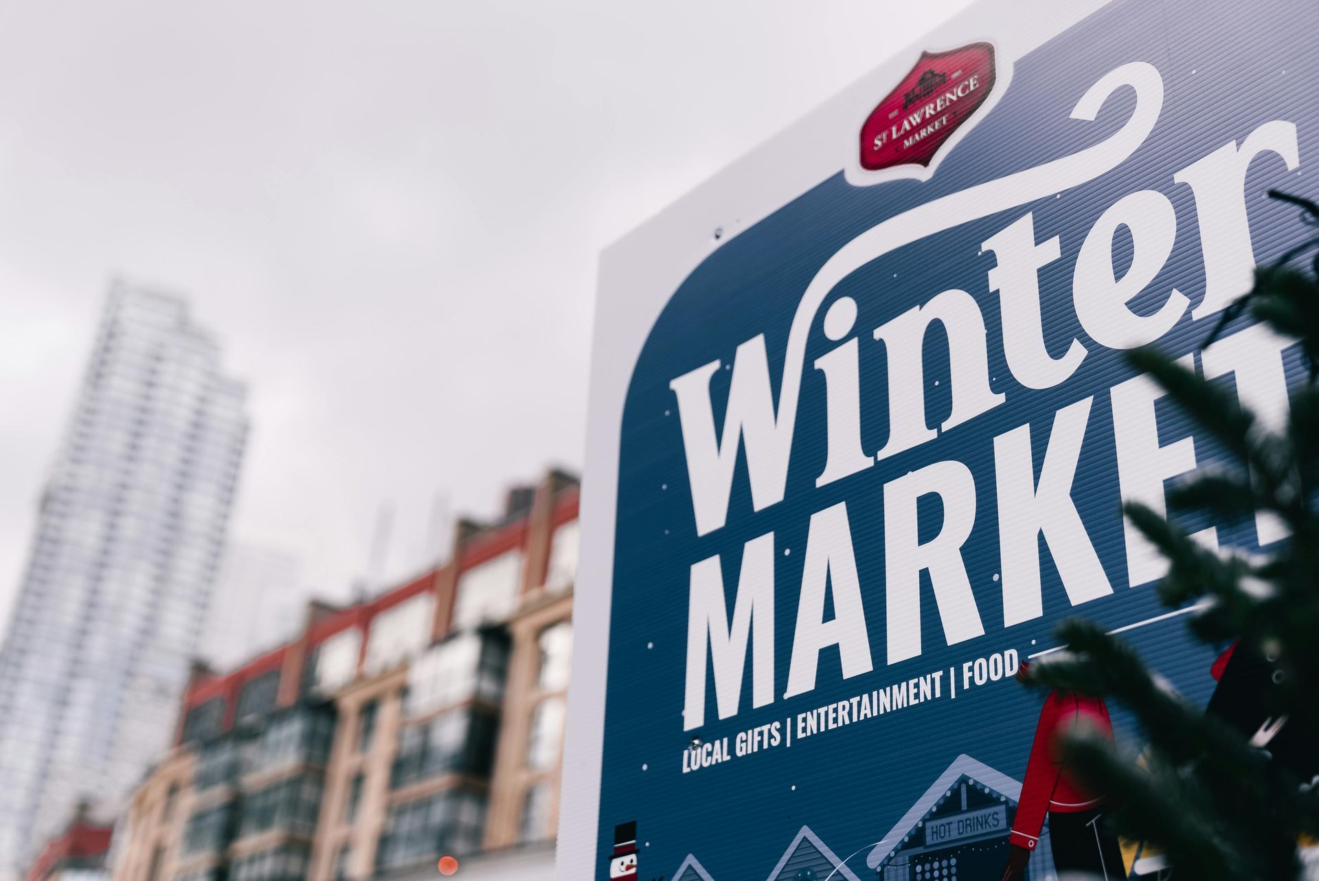 Sign for a Winter Market with buildings in the background. It reads