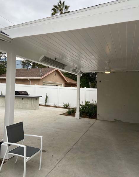 A patio with a chair and a table under a covered patio.