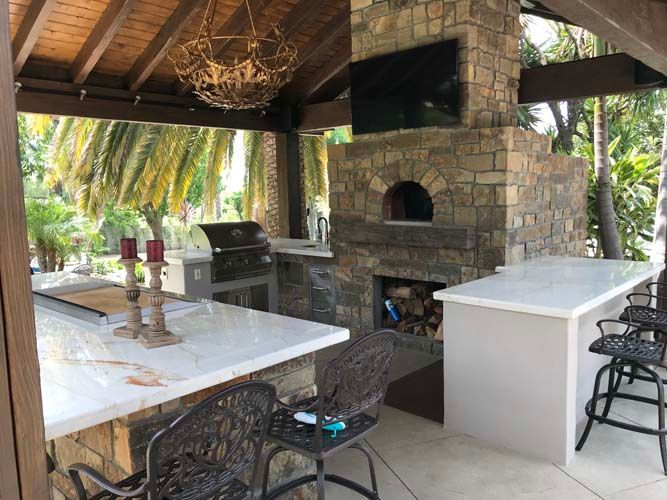 A large outdoor kitchen with a pizza oven and a grill.