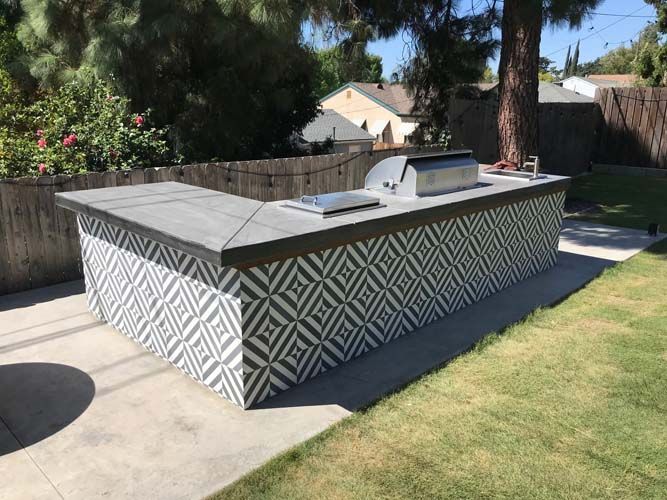A large outdoor kitchen in a backyard with a grill.