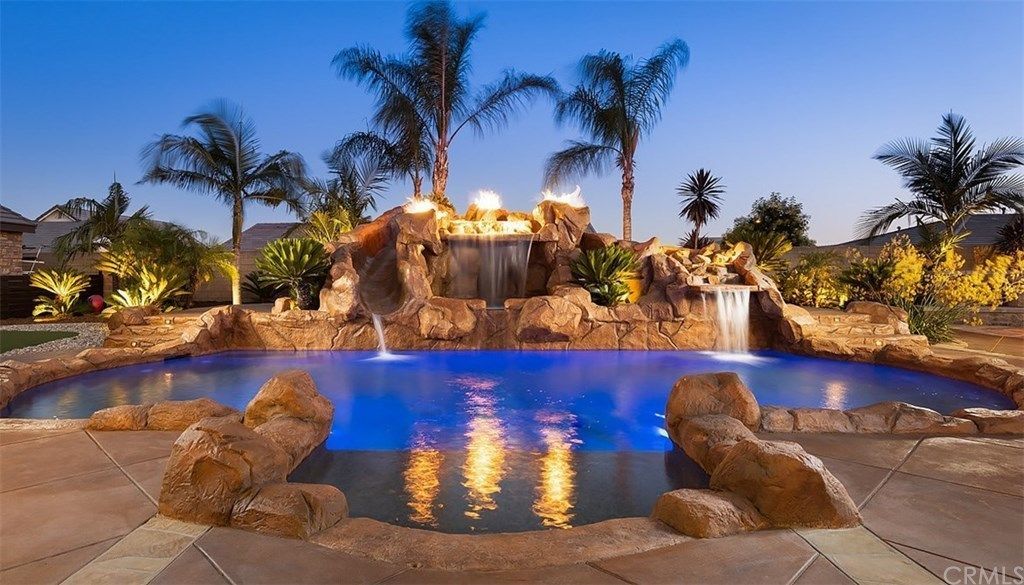 A large swimming pool with a waterfall and palm trees in the background