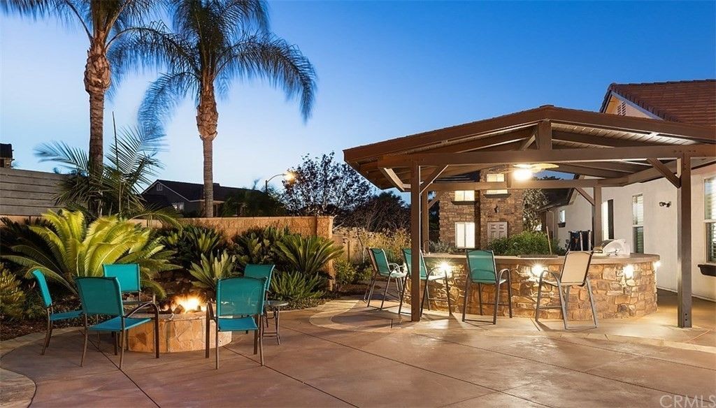 A patio with a fire pit and chairs under a pergola
