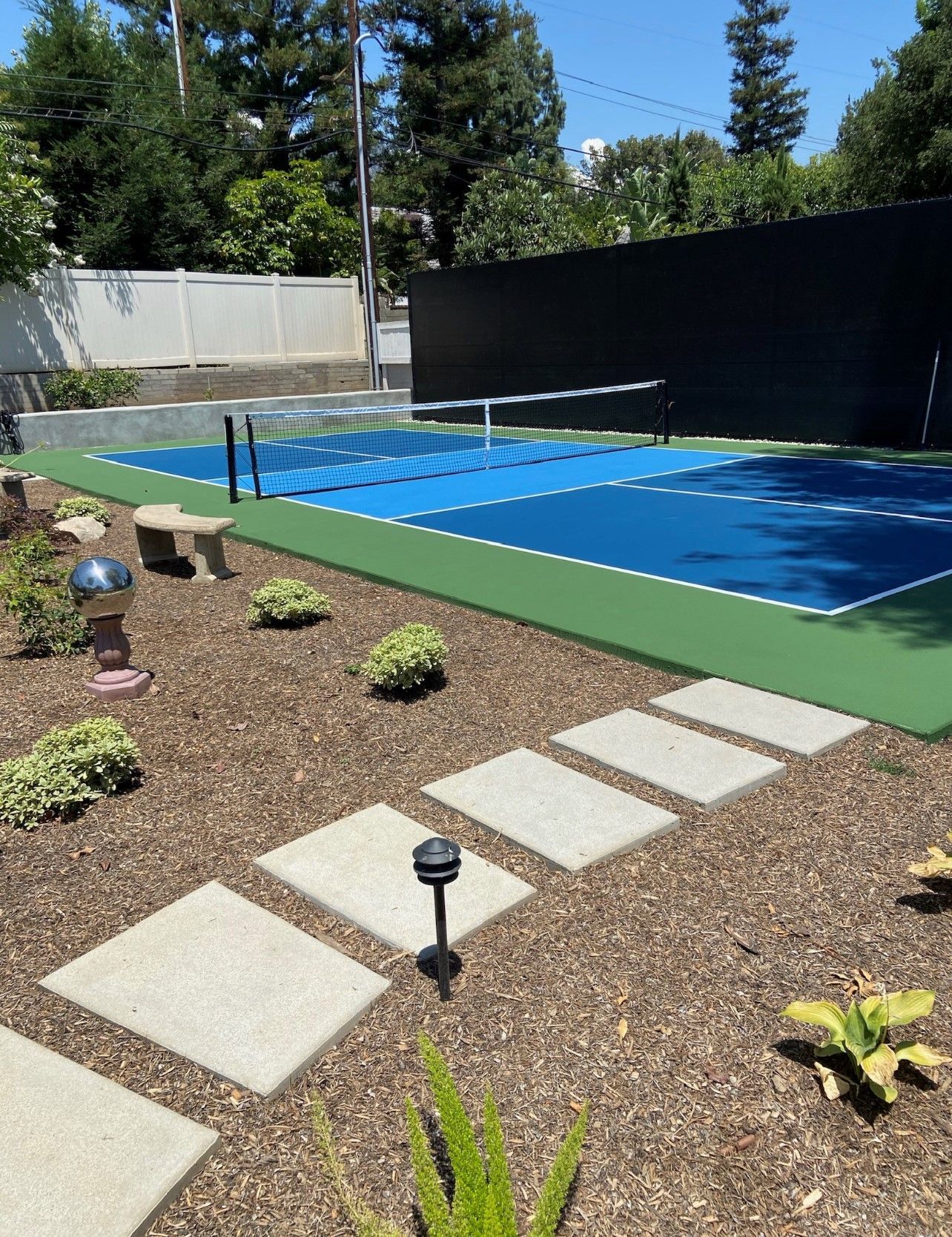 A backyard with a tennis court and a volleyball net