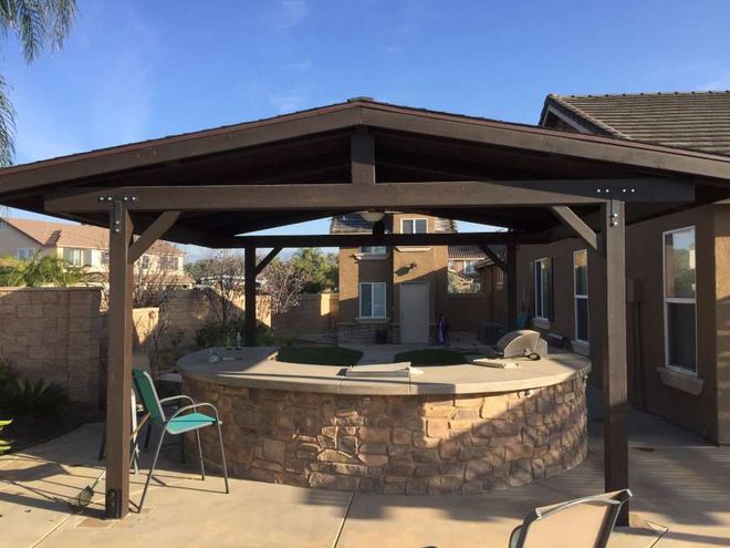 An outdoor kitchen with a fireplace and a flat screen tv.