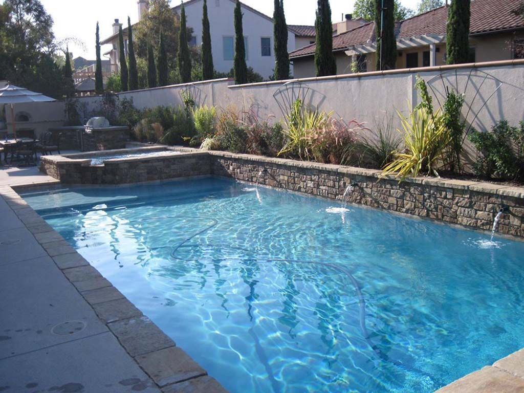 A large swimming pool with a stone wall surrounding it