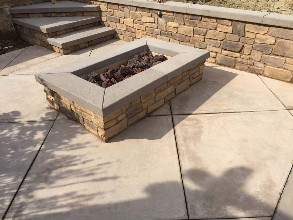 An outdoor kitchen with a fireplace and a flat screen tv.