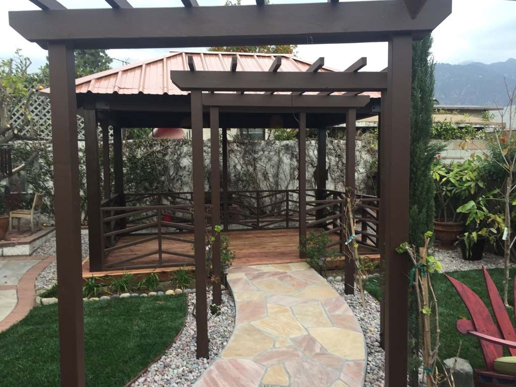 An outdoor kitchen with a fireplace and a flat screen tv.