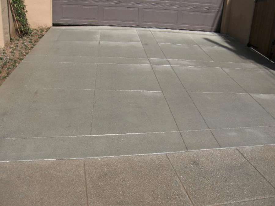 A concrete driveway with a garage door in the background