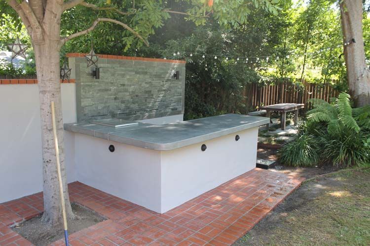 A wooden broom is sitting next to a tree in a backyard.